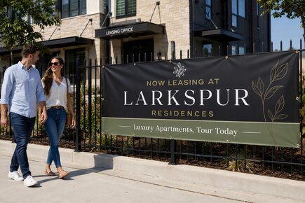 Custom fence banners outside an apartment community promoting leasing an open house property tours and move in specials