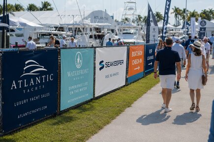 Fence banners at a boat show displaying marina advertising sponsor branding check in directions and vip lounge information