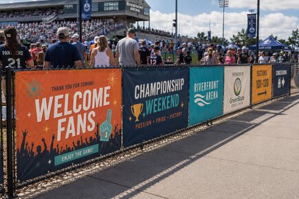 Soccer field fence banners at a youth tournament displaying team welcome messaging sponsor logos sportsmanship reminders and field directions
