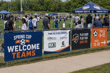 Sports venue fence banners welcoming fans and displaying championship weekend branding sponsor logos seating directions and concessions
