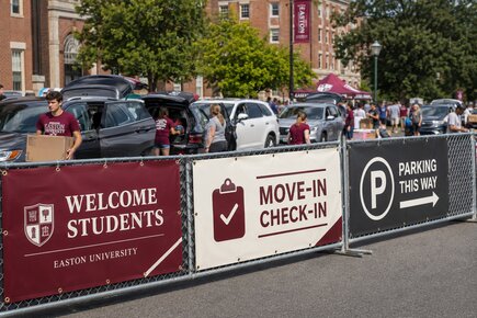 University fence banners on chain link fencing directing students to move in check in and parking during campus move in day