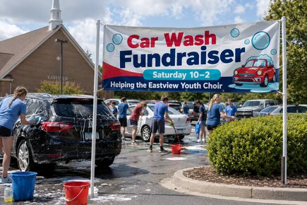 Custom fundraiser vinyl banner advertising an Eastview Youth Choir car wash outside a community event