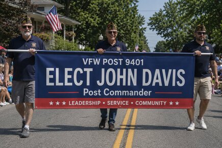 Custom parade vinyl banner for VFW Post 9401 promoting John Davis for Post Commander, carried by members during a community parade